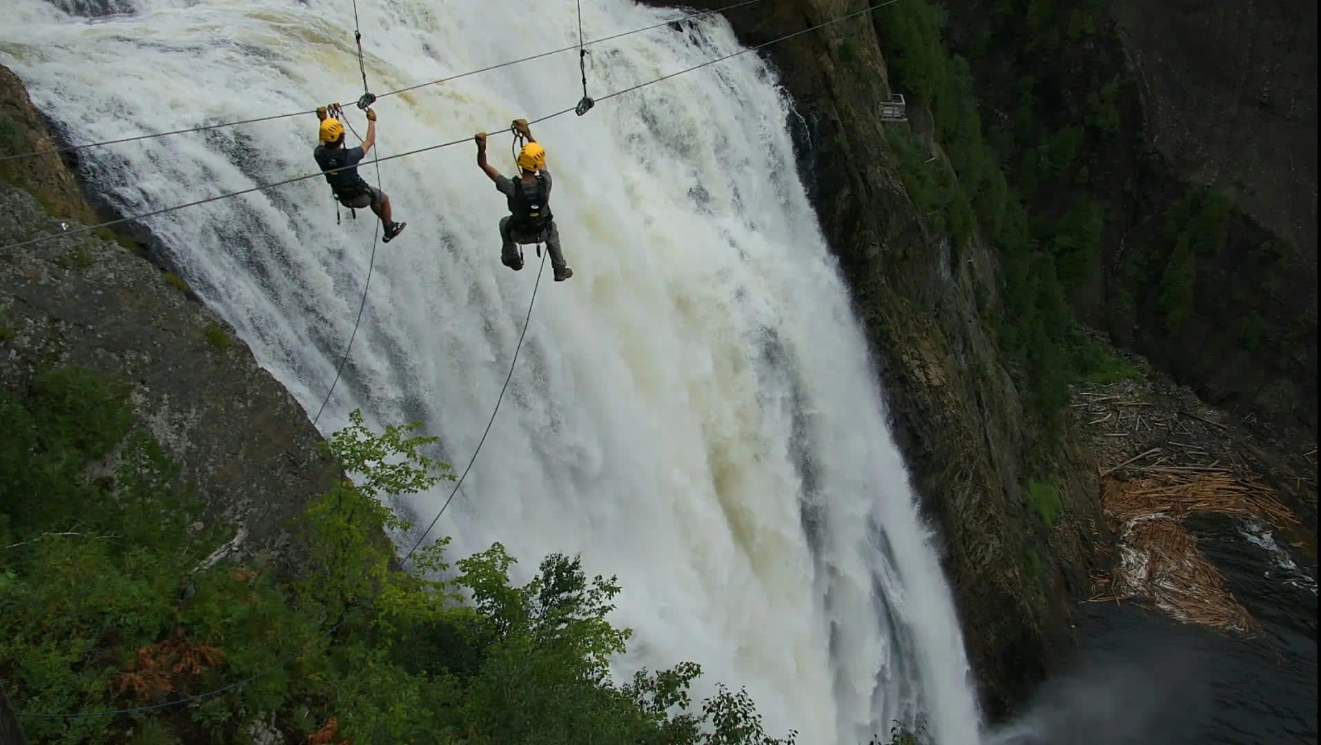 Man zip-lining over a waterfall, Chutes Boyoma