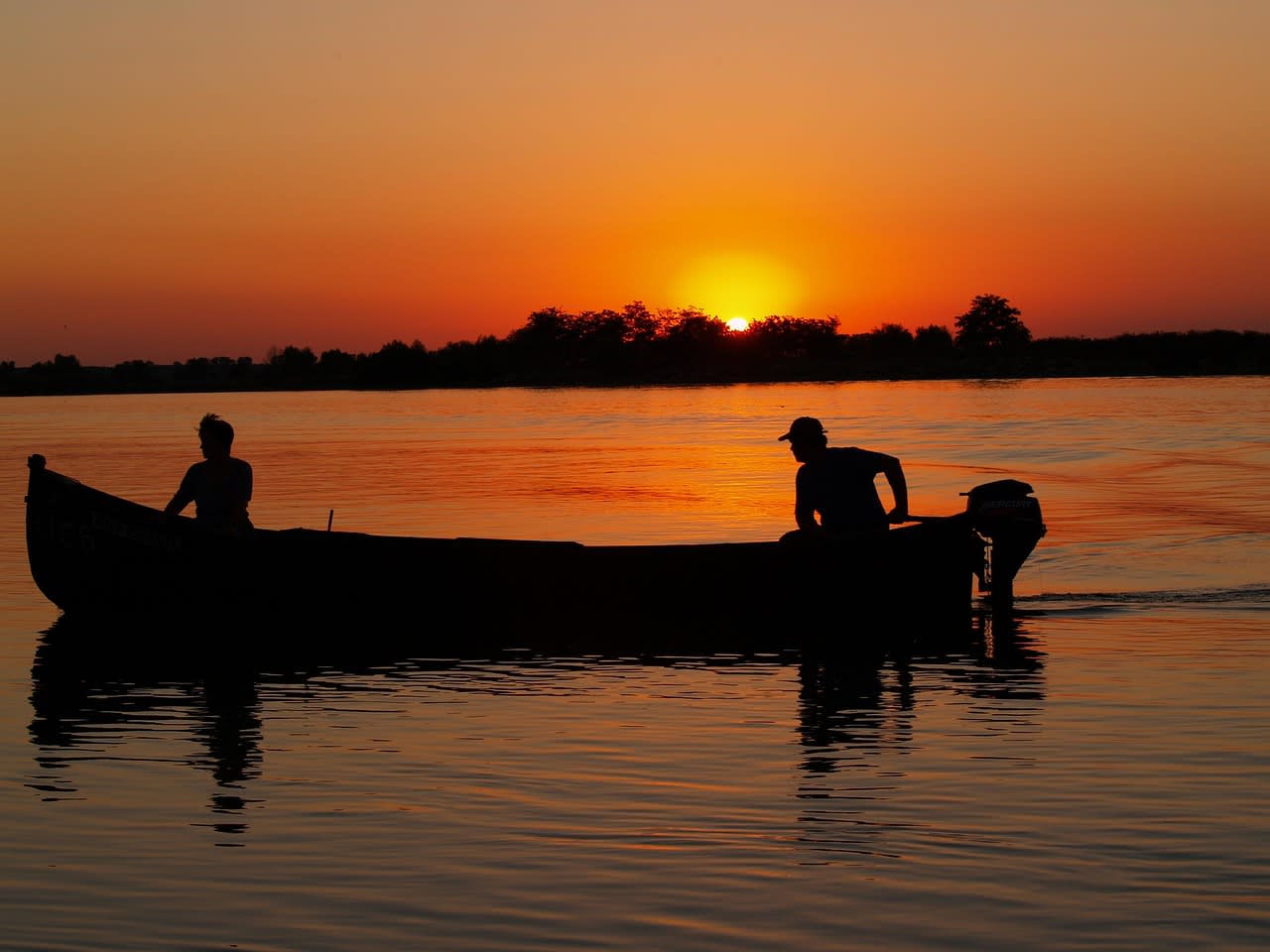 Traditional wooden boat navigating the narrow channels through dense reed beds of the Danube Delta