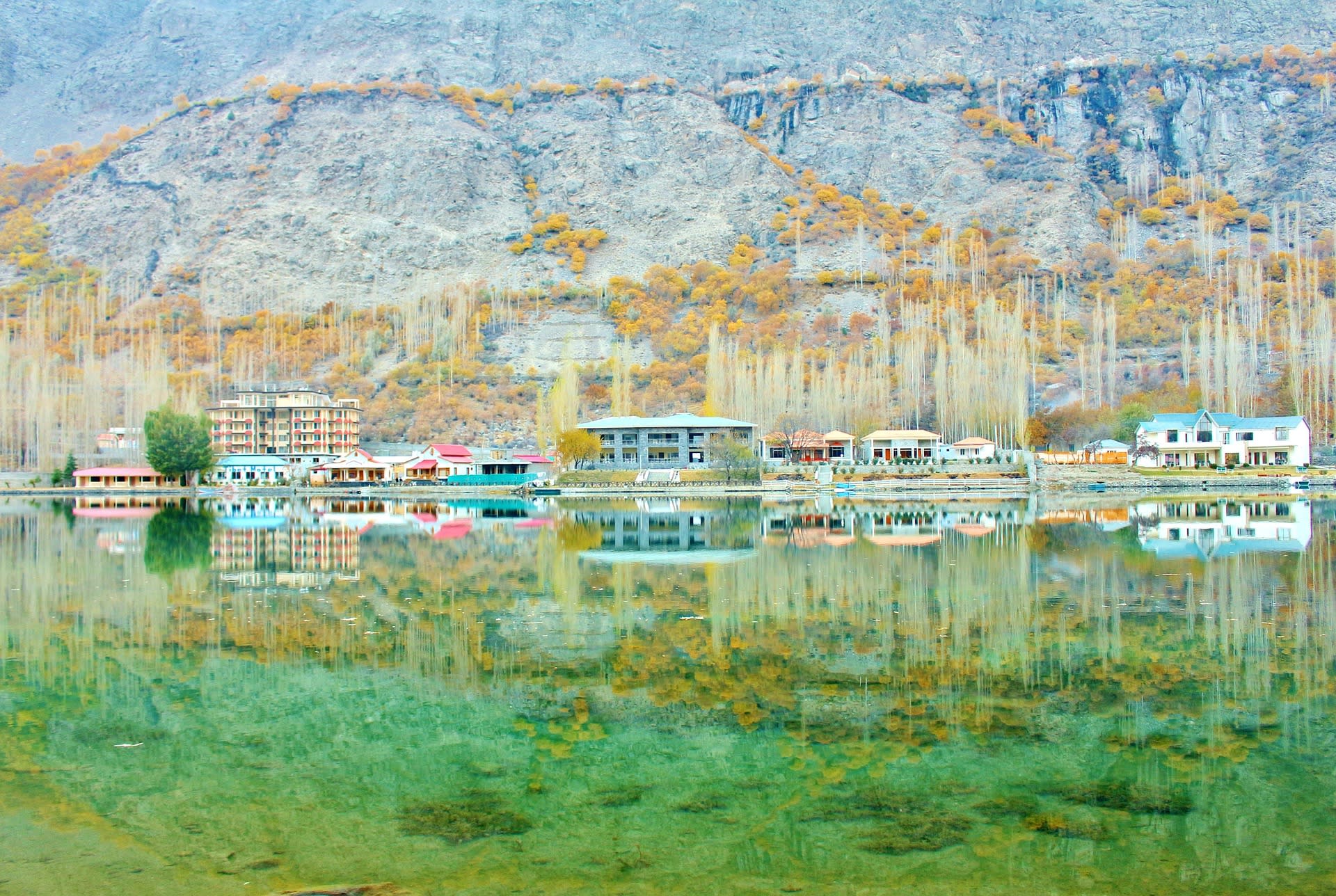 Mirror reflection of mountains and trees in the still waters of Lake Shangrila, Pakistan