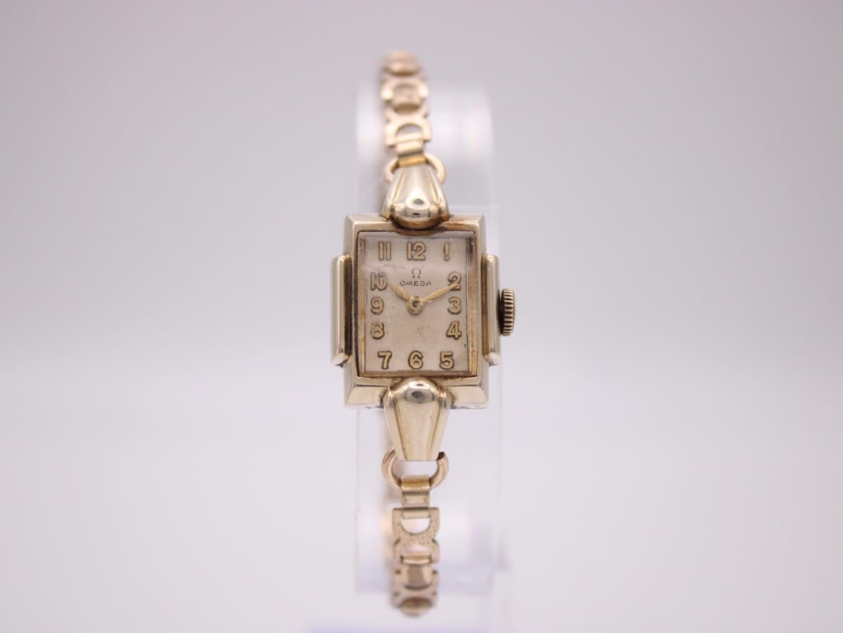 Front view of vintage Omega 3898-2 rectangular gold-plated watch with champagne dial and gold-tone bracelet.