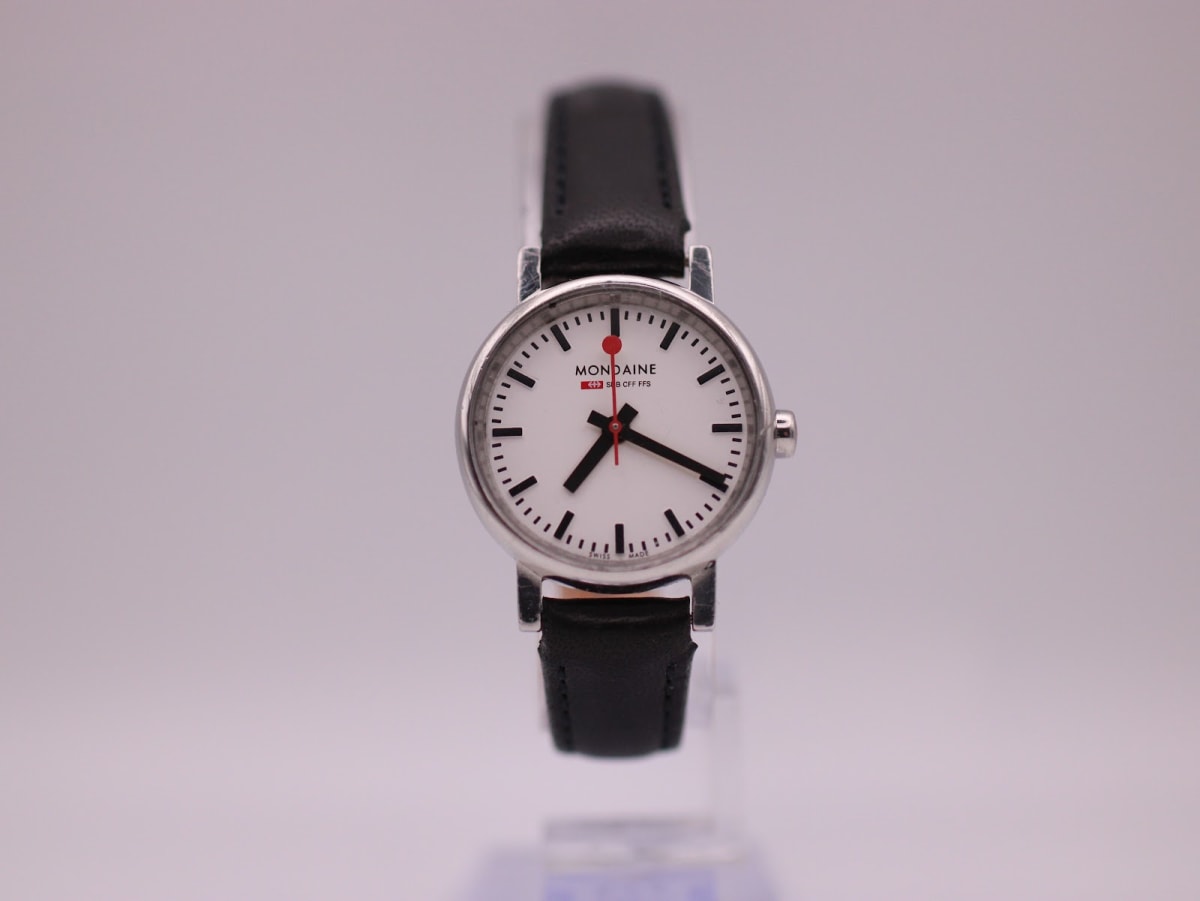 Front view of the Mondaine Official Swiss Railways Watch with a white dial, black hands, and red lollipop seconds hand on a black leather strap.