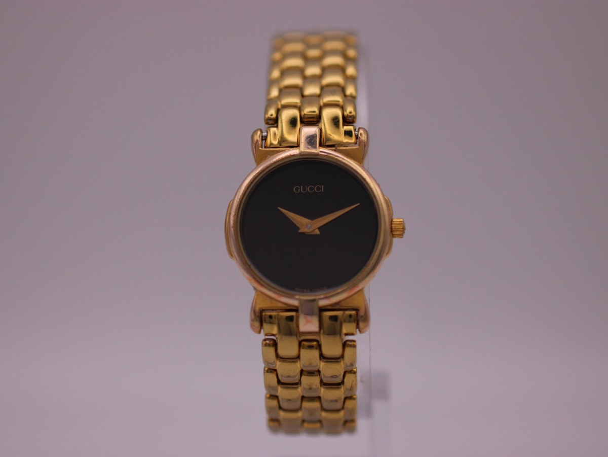 Front view of the vintage Gucci 3400 L watch with a gold-tone case and bracelet, featuring a black dial and gold hands.