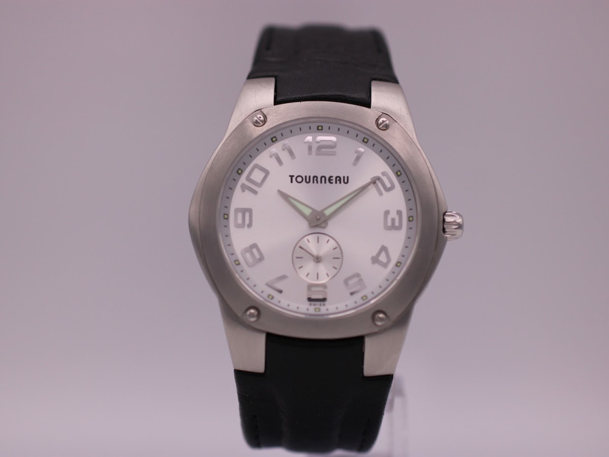 Front view of the Tourneau Gap Inc. watch, showcasing the silver dial, bold numerals, brushed steel case, and black leather strap.