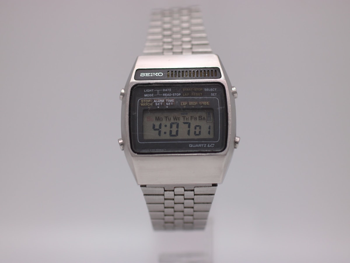Front view of vintage Seiko A159-5009-G digital LCD watch with silver stainless steel case and bracelet, showing 4:07:01 on display.