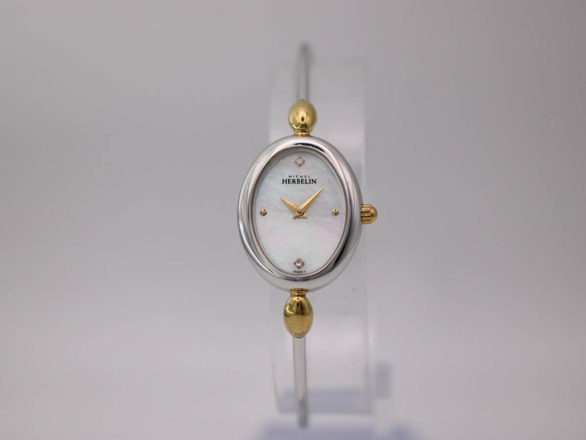 Front view of the Michel Herbelin 7003 watch with oval silver-tone case, gold-tone accents, and cream mother-of-pearl dial.
