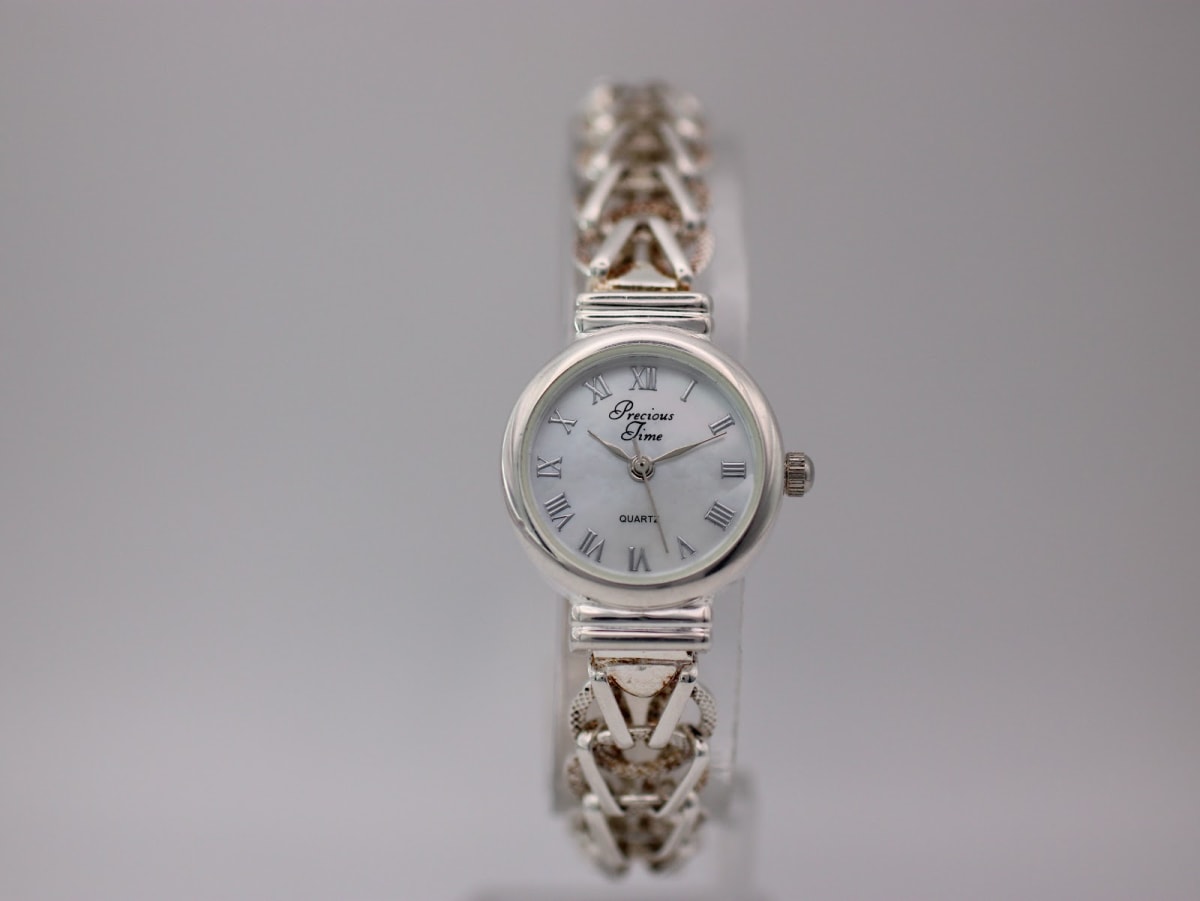 Front view of Precious Time watch with silver-tone case and braided bracelet