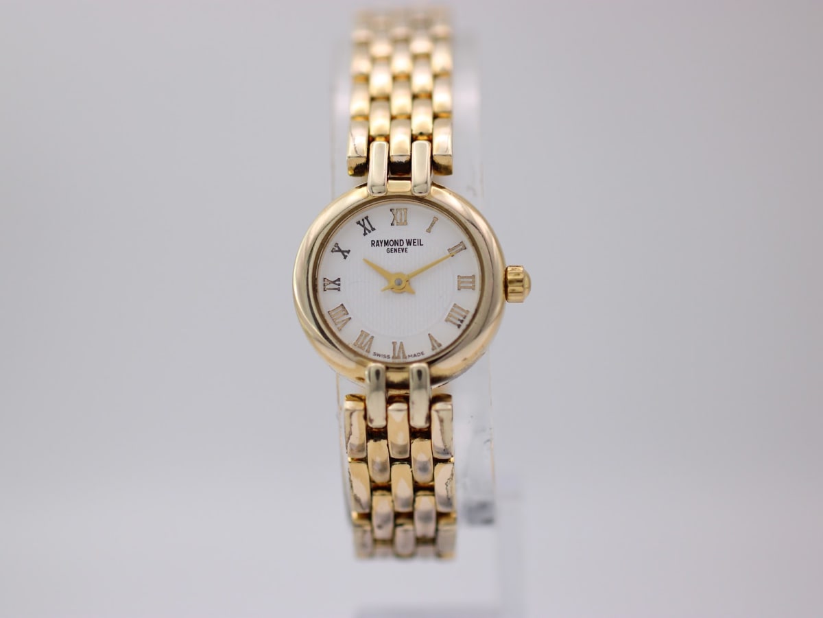 Front view of Raymond Weil 5892 ladies watch with gold-tone case and bracelet on a clear stand.
