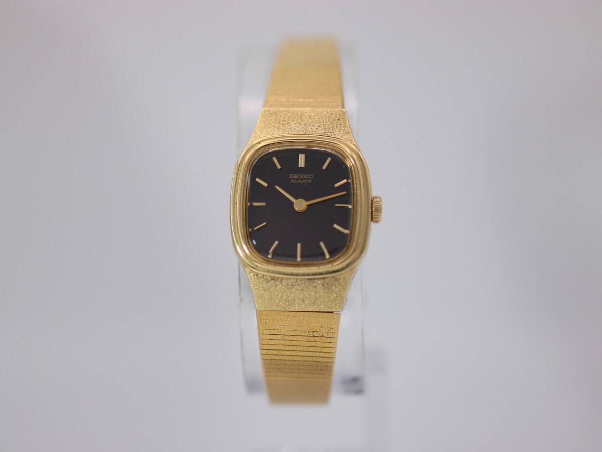 Front view of the gold tone Seiko ladies' quartz watch with black rectangular dial and integrated mesh bracelet.