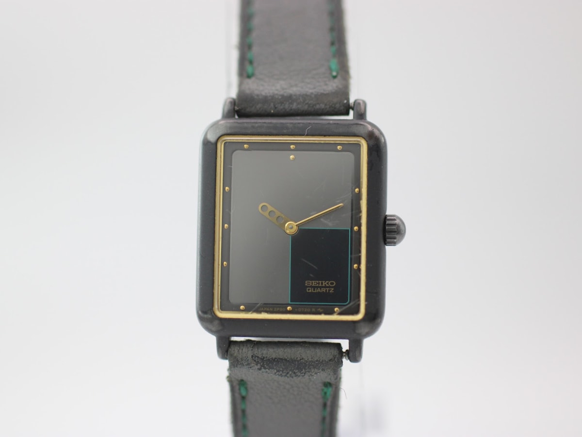 Front view of the Seiko 2P20-5470 watch, showing the black rectangular dial, gold inner bezel, and black leather strap.