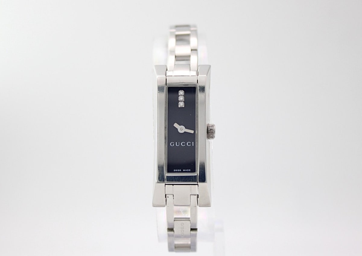 Front view of the Gucci 110 watch, showing the silver-tone rectangular case, black dial with three diamond accents at 12 o'clock, and stainless steel bracelet.
