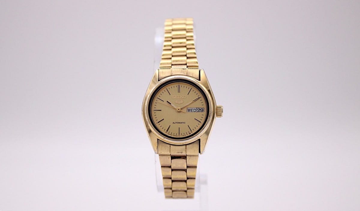 Front view of the Seiko 2906-0850 automatic watch with a gold-tone dial and steel bracelet, presented on a white background.