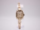 Front view of vintage Omega 3898-2 rectangular gold-plated watch with champagne dial and gold-tone bracelet.