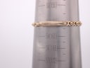 The gold-tone bracelet of the Omega watch measured on a wrist sizing gauge, showing a circumference of approximately 15.3cm.
