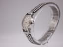 Side profile view of the Omega Ladymatic watch on a clear stand, showing the signed crown and steel bracelet.