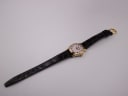 Top-down view of the entire Raymond Weil watch and strap, showing the gold buckle at the end.