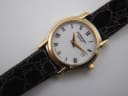 Close-up of the Raymond Weil watch dial, showing the roman numerals, gold hands, date window, and 'swiss made' text.
