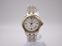 Front view of Tissot Ballade ladies' two-tone watch with white dial and gold-tone Roman numerals on a display stand.