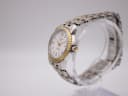 Angled side view of the Tissot Ballade watch on a stand, showcasing the fluted gold PVD bezel and two-tone bracelet.