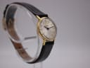 Another angled side view of the Tissot watch, showing the crown and the curve of the black leather strap.