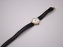 Overhead view of the Tissot watch with the black leather strap laid out flat, showing its full length.
