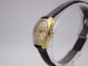 Side profile of the rectangular gold-tone Tissot watch case and original crown.