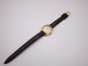 Overhead view of the Tissot watch with its full length brown crocodile-effect leather strap laid flat.