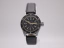 Front view of the CASWATCH manual wind diver-style watch with black dial, silver case, and black leather strap on a stand.