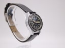 Another angled side view of the CASWATCH watch, showing the case profile and black leather strap.