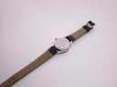 Back view of the CASWATCH watch, showing the stainless steel case back and the "genuine leather" marking on the strap.