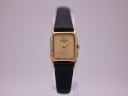 Front view of the Raymond Weil 5700 ladies watch, showing its rectangular gold electroplated case and champagne dial with a black leather strap.