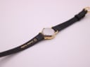 Close-up of the watch's reverse, showing the strap with "10 Genuine Leather" text and the case back.