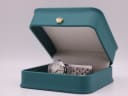 The Jaquet-Droz watch nestled inside its original green presentation box with a gold crown emblem.