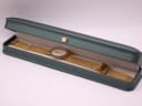 The gold-tone Toy Watch displayed inside its original dark green presentation box.