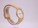 Another angled side view of the Toy Watch on a clear stand, highlighting its slim profile.