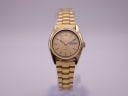Front view of gold-tone Seiko 5 automatic watch with gold sunburst dial and day/date display.