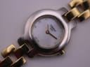 Close-up of the Tissot G330 dial, showing the white mother-of-pearl effect, gold hands, Tissot logo, and 8 gem-set hour markers.
