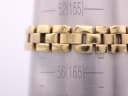 Close-up of the Tissot G330 bracelet links on a metal sizing gauge, showing the gold-tone finish and link design.