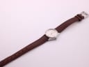 Overhead view of the Favre Leuba watch with its full brown leather strap laid flat on a white background.