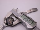 Digital caliper measuring the watch case diameter at 26.5mm, alongside the watch.