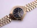 Top-down view of the gold-toned Seiko watch with bracelet extended, highlighting the black dial.