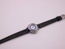 Top-down view of the Craftsman watch and its long black leather strap laid flat on a white surface.
