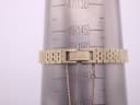 The gold-tone integrated bracelet of the Seiko watch on a wrist sizing gauge, showing a circumference measurement of 15.5cm.