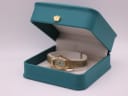 The Seiko watch displayed in a green leatherette studio presentation box with a gold crown emblem.