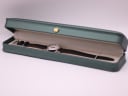 The Mondaine watch resting inside a generic green leatherette presentation box with a gold crown emblem.