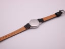 Rear view of the Mondaine watch, showing the stainless steel case back and the light brown underside of the black leather strap.