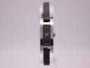 Front view of Gucci 3900L watch with rectangular silver-tone case, black minimalist dial, and black leather strap.