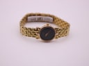 Full view of the gold-tone Gucci 3400 L watch on a clear stand, positioned centrally against a light background.