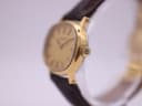 Angled close-up of the Tissot watch showing the gold tonneau case and signed winding crown.