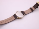 Rear view of the watch showing the stainless steel case back and "Genuine Leather" marking on the brown strap, lug width 15mm visible.