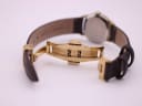 Close-up of the gold-tone deployant clasp on the brown leather strap.